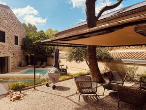 Ein Poolbereich mit Pergola, Sitzgelegenheiten im Freien und einem Steinhaus.