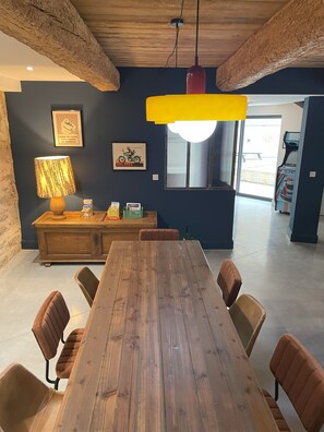 Ein Essbereich mit Holztisch und -stühlen, einer Lampe und Kunstwerken an der Wand.