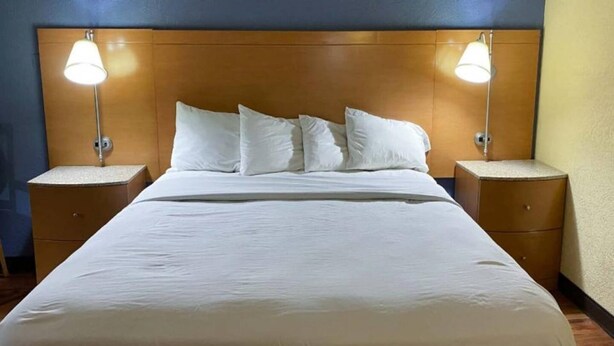 A hotel room with a large bed, two bedside tables, and two wall-mounted lamps. - 1 King Bed | Non-Smoking, Micfridge (Savannah GA)