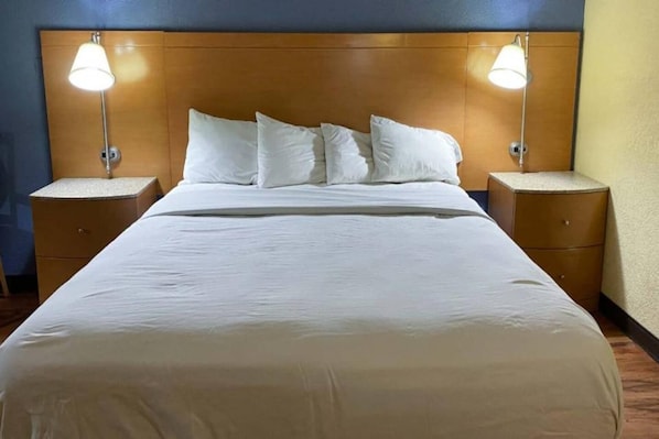 Ein Hotelzimmer mit einem großen Bett, zwei Nachttischen und zwei Wandlampen.