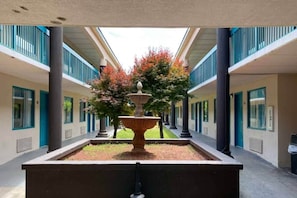 A courtyard with a central fountain, surrounded by a building with multiple balconies and windows. - 1 King Bed | Non-Smoking, Micfridge (Savannah GA)
