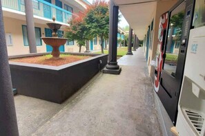 A covered walkway with a fountain, columns, and a building with blue accents. - 1 King Bed | Non-Smoking, Micfridge (Savannah GA)