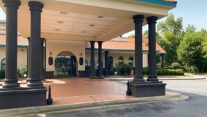A building with a covered entrance, columns, and a tiled roof. - 1 King Bed | Non-Smoking, Micfridge (Savannah GA)