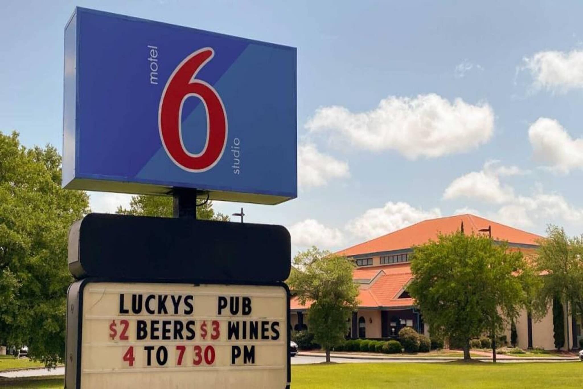 A motel sign with a number 6 and a Luckys Pub sign below it.