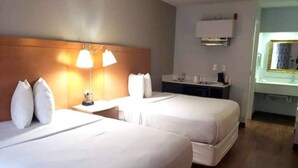 A hotel room with two beds, a nightstand, a lamp, a mirror, and a small table. - 2 Queen Beds | Non-Smoking, Micfridge (Savannah GA)