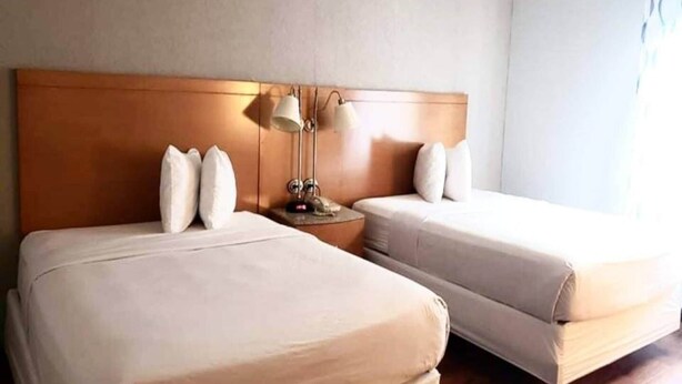 A hotel room with two beds, a wooden headboard, bedside lamps, and a nightstand. - 2 Queen Beds | Non-Smoking, Micfridge (Savannah GA)