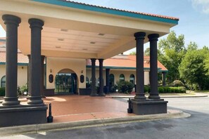 Un edificio con entrada cubierta, columnas y techo de tejas.