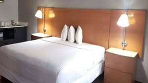 A hotel room with a large bed, two bedside tables, and two wall-mounted lamps. - 1 King Bed | Suite, Non-Smoking, Micfridge (Savannah GA)