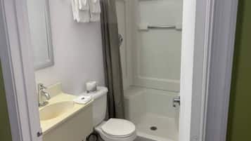 A small bathroom with a toilet, sink, and shower.