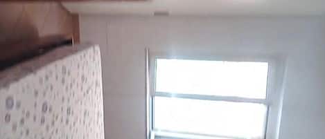 Una habitación con ventana, pared con diseño y techo de madera.