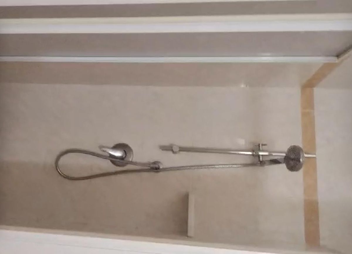 Una dutxa amb plat de robaç i aixeta de pared.
