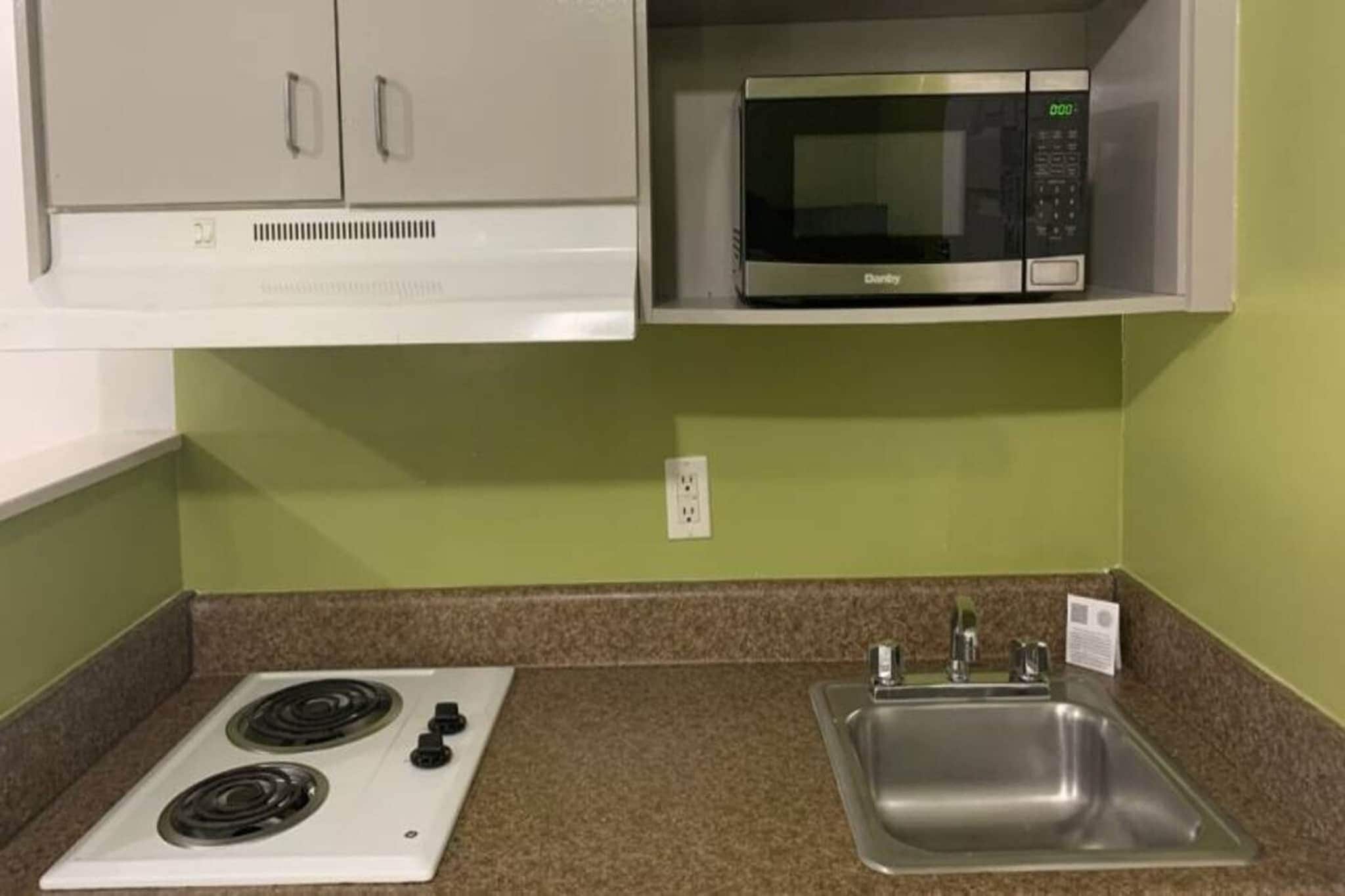 A kitchenette with a stove, microwave, and sink.