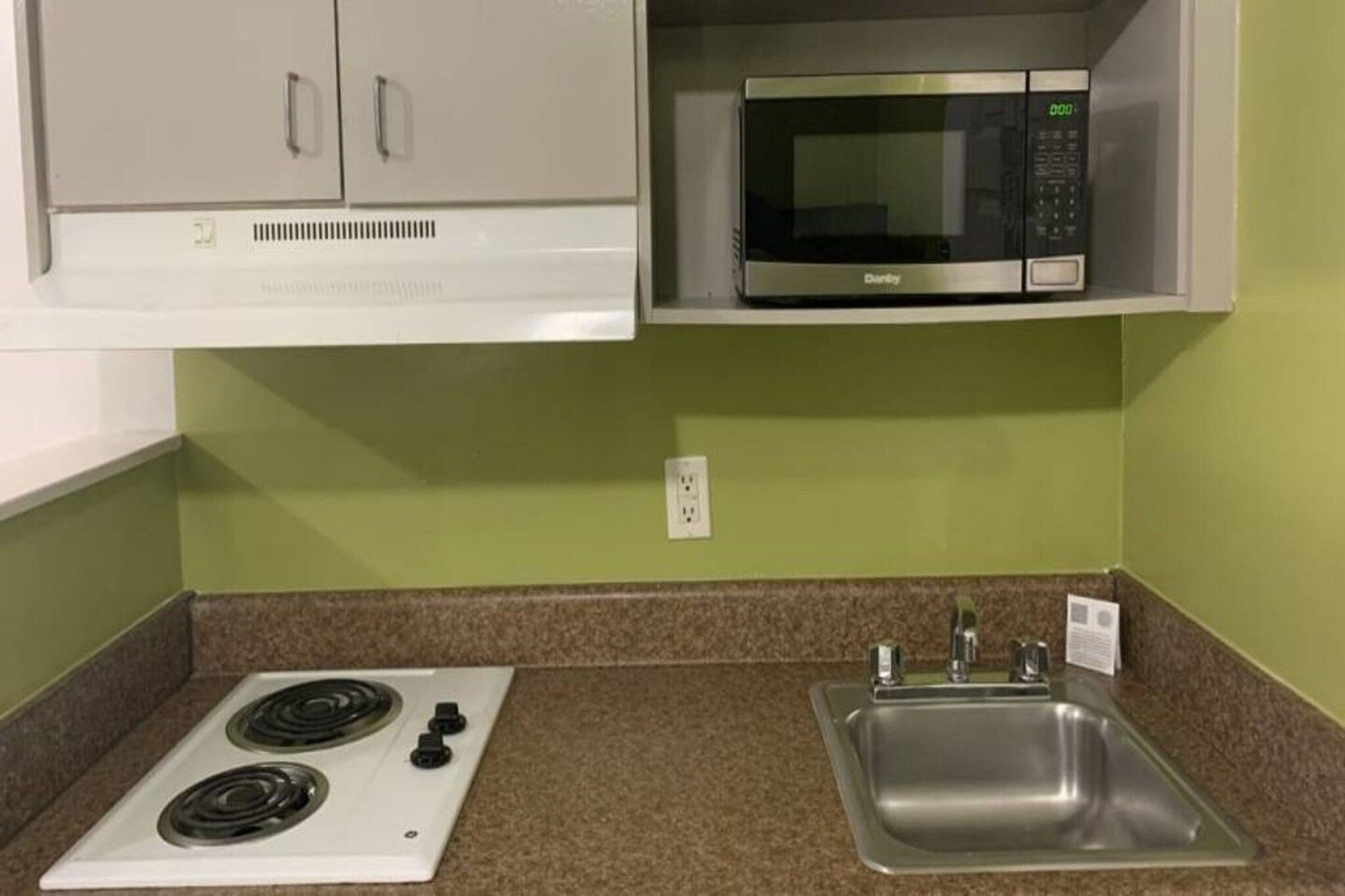 Una kitchenette con estufa, microondas y pileta.