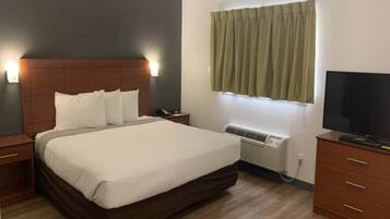 Habitación de hotel con cama, mesitas de noche, televisión, aire acondicionado y ventana con cortinas.