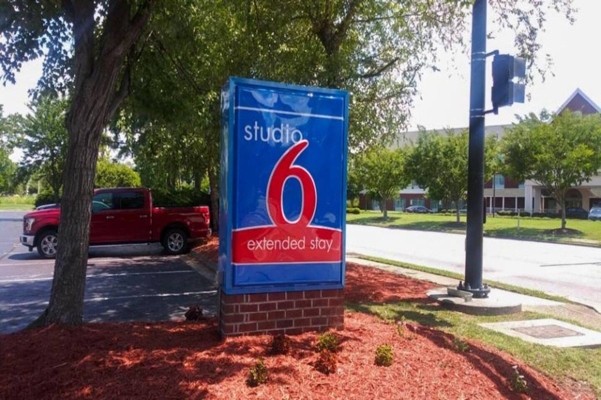 Señalización para un hotel Studio 6 de estancia prolongada, con base de ladrillo y fondo azul.