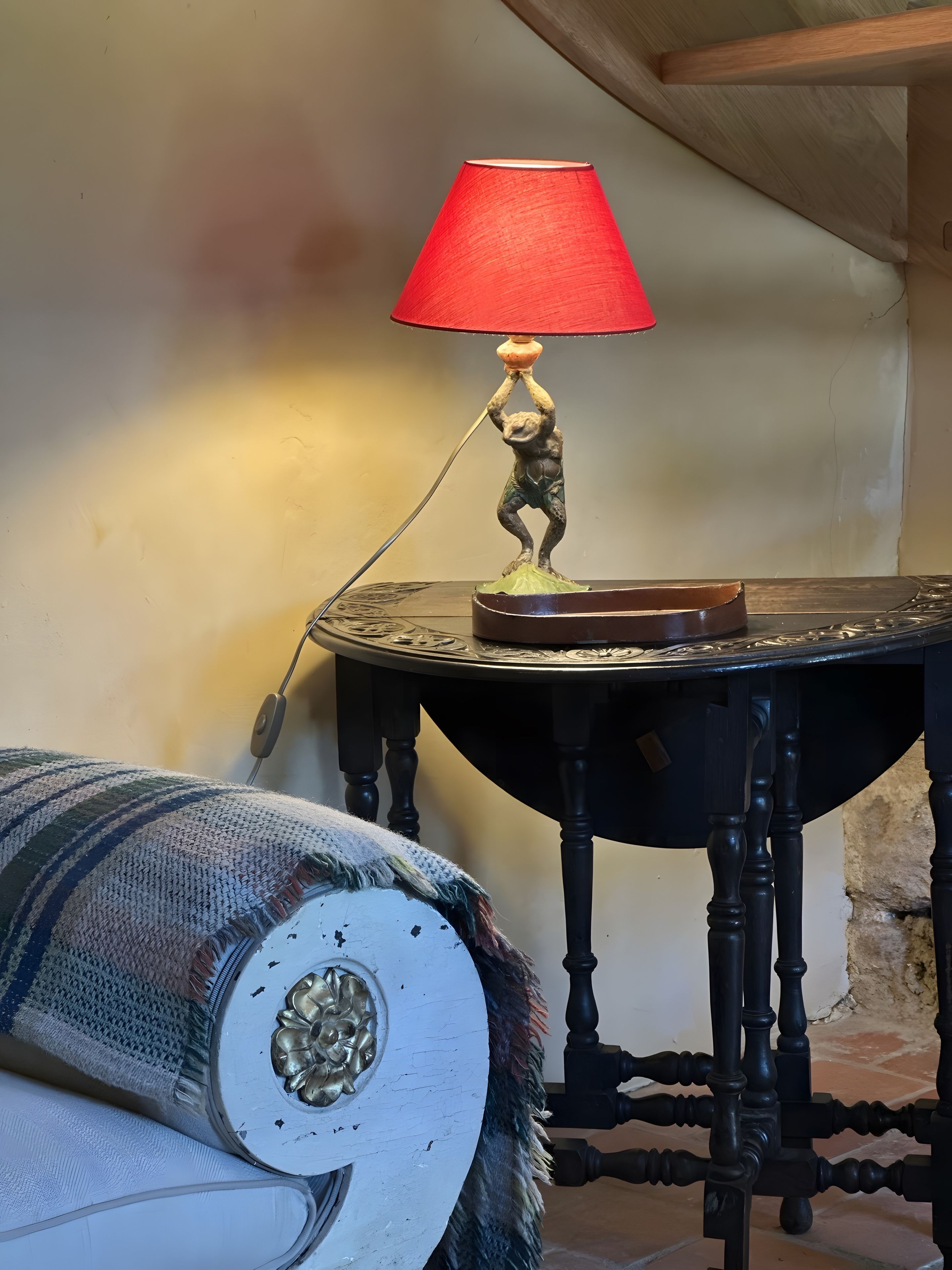 Uma mesa com uma luminária e um objeto decorativo.