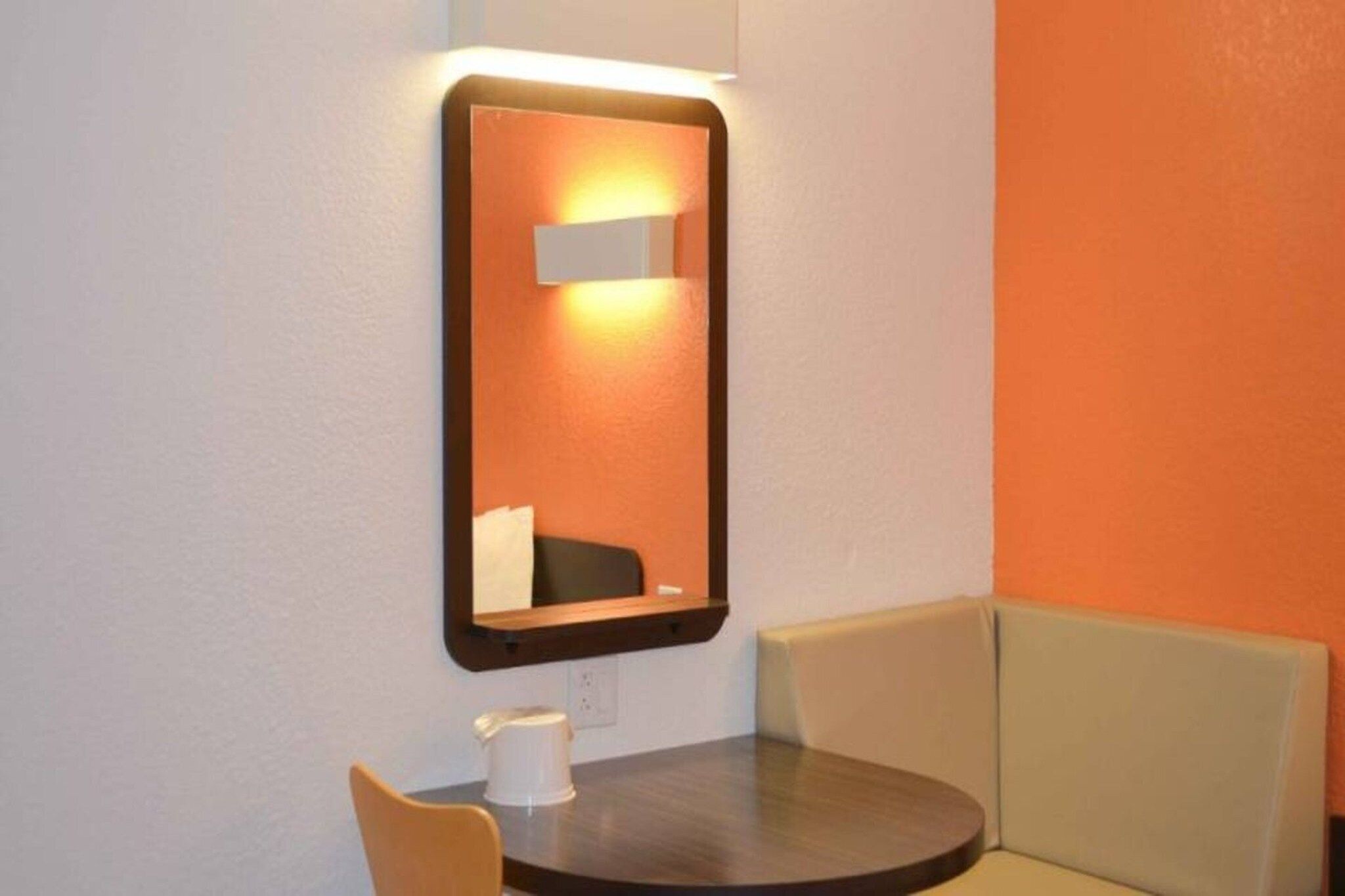 Une petite table avec une chaise, un miroir et une boîte de mouchoirs.