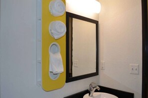 A bathroom with a yellow towel rack holding three white towels, a mirror with a black frame, and a white sink with a silver faucet. - 2 Queen Beds | Non-Smoking, Micfridge (KINGSLAND)