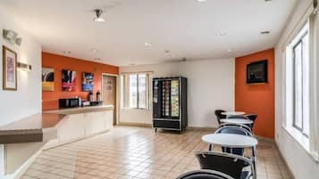 Ein Café mit Theke, Sitzbereich und einem Getränkeautomaten.