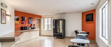 A cafe with a counter, seating area, and a vending machine.