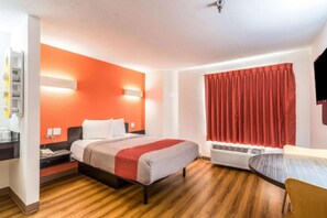 Ein Hotelzimmer mit Bett, Nachttisch und einem roten Vorhang.