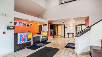 A hotel reception area with a counter, a fire alarm, and a staircase.