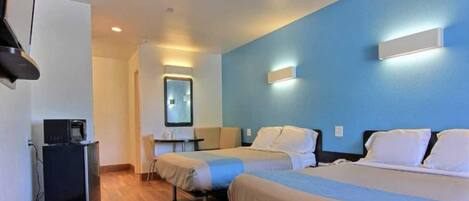A hotel room with two beds, a desk, a chair, a television, and a mirror.