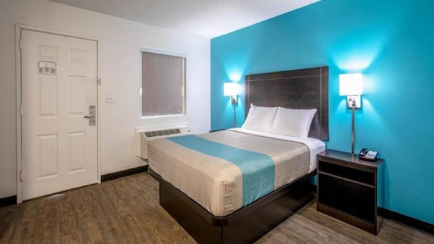 A hotel room with a bed, bedside lamps, a nightstand, a window, and a door. - 1 Queen Bed|Premium,Kitchen,Nsmk (Greenville)
