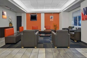 A lobby with a reception desk, seating area, and a television screen. - 1 Full Bed | ADA/RI Shower (Orlando FL)