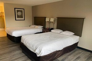 Habitació d'hotel amb dos llits, una tauleta de nit, una làmpada i un quadre a la paret.