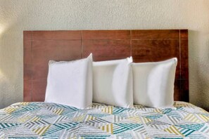 A bed with a patterned bedspread and a wooden headboard.