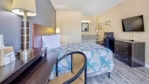 A hotel room with a bed, bedside table, chair, desk, lamp, TV, dresser, and a non-smoking sign. - 1 Queen Bed | Non-Smoking, Micfridge (Effingham)