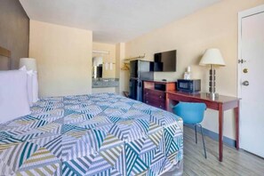 Ein Hotelzimmer mit einem Bett, einem Schreibtisch, einem Stuhl, einem Fernseher und einer Tür.