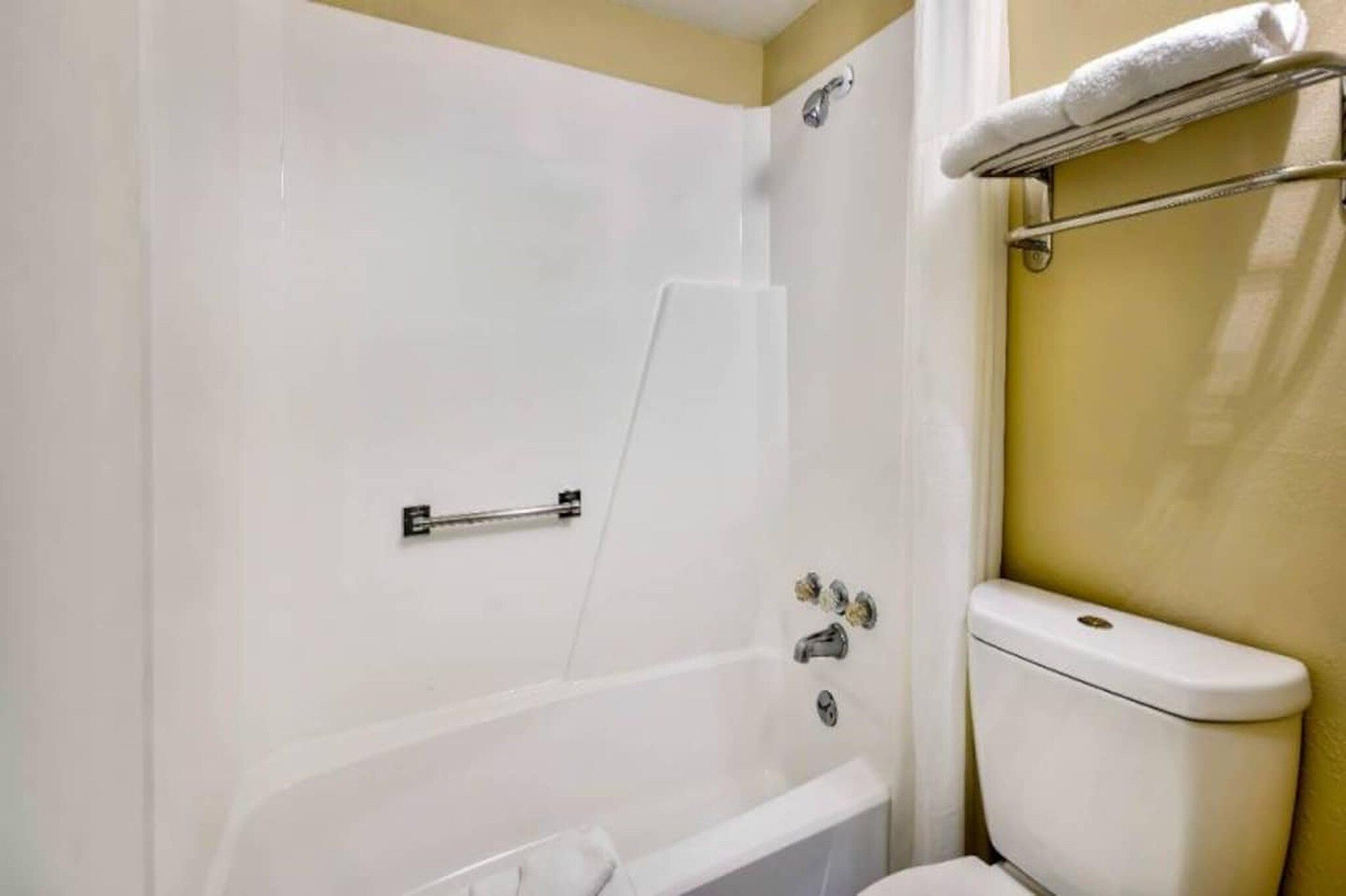 A bathroom with a bathtub, toilet, and a towel rack.