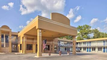 A hotel with a covered entrance, American flags, and a parking lot.