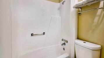 A bathroom with a bathtub, toilet, and a towel rack.