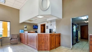 A reception area with a wooden counter, a chair, a television, and a clock on the wall. - 1 King Bed | Non-Smoking, Micfridge (Effingham)
