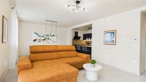 Ein Wohnzimmer mit einer Couch, einem kleinen Tisch mit einer Pflanze und Kunstwerken an den Wänden.