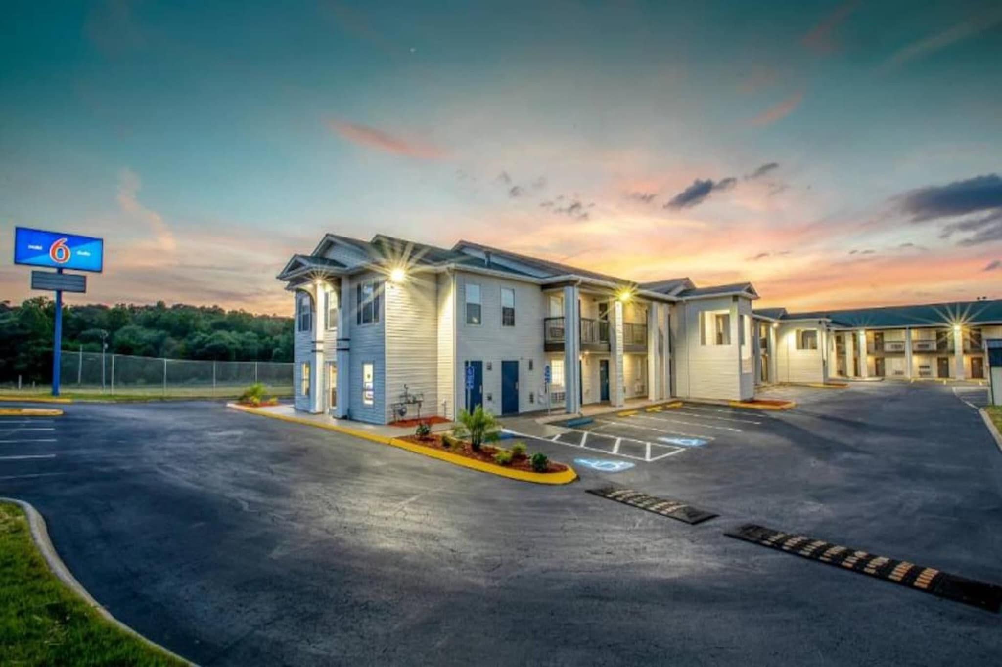 A motel with a parking lot, multiple buildings, and a sunset sky.