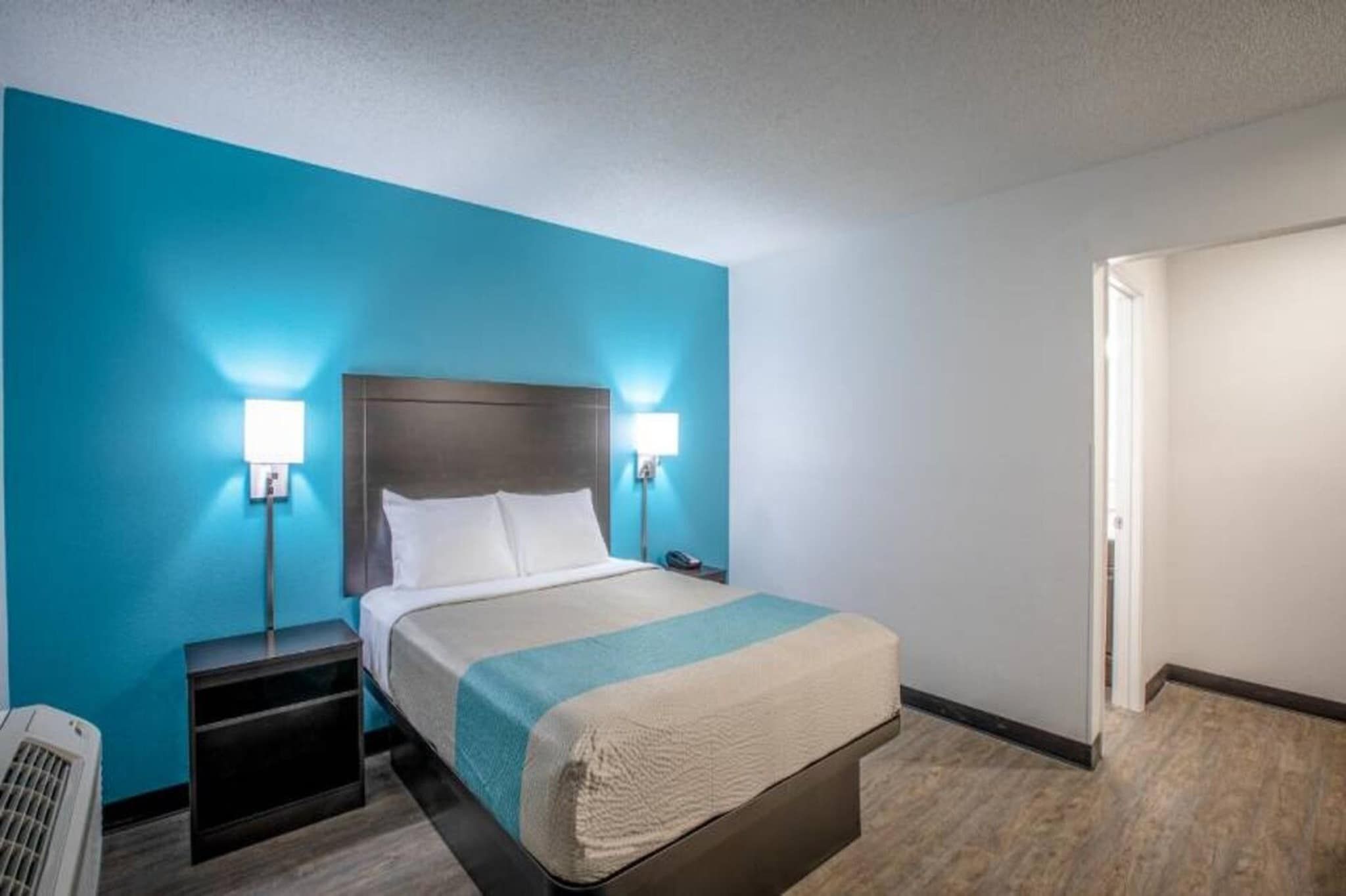 A hotel room with a bed, bedside tables, and a nightstand.