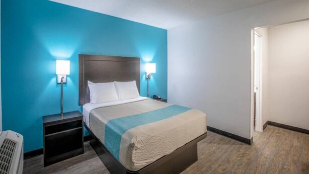 A hotel room with a bed, bedside tables, and a nightstand. - 1 Queen Bed|Micfridge,Non-Smoking (Greenville)