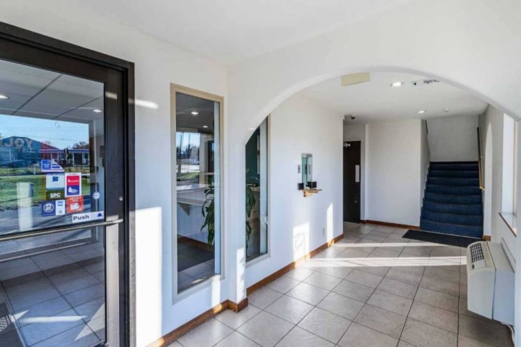 A modern interior with a tiled floor, a staircase, and a glass door with a 'Push' sign.