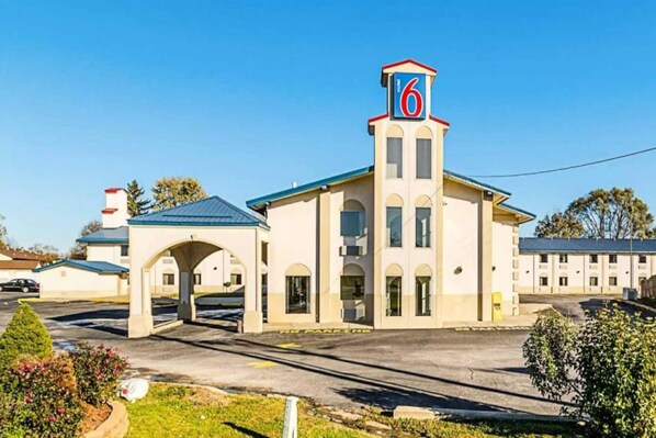 A motel with a prominent '6' sign, a covered parking area, and a clear sky.