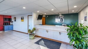 Un área de recepción con mostrador, televisor y un cartel en la pared.