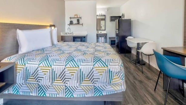 A hotel room with a bed, a desk, a chair, a kitchenette, and a bathroom. - 1 King Bed | Non-Smoking, Kitchen (Effingham)