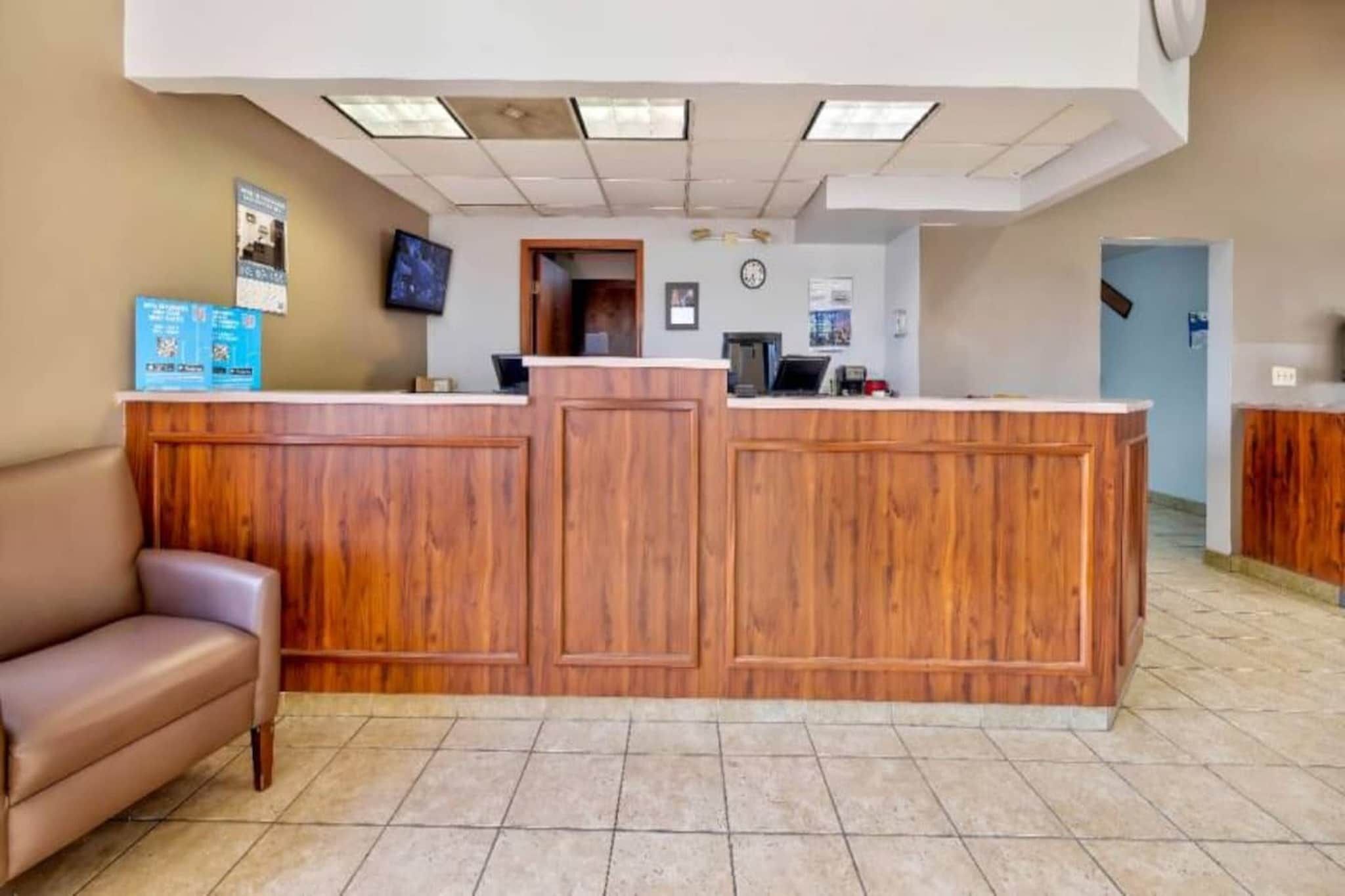 A reception desk with a wooden finish, a brown leather couch, and a tiled floor.
