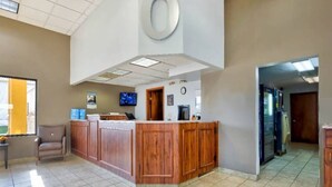 A reception area with a wooden counter, a clock, and a television on the wall. - 1 King Bed | Non-Smoking, Kitchen (Effingham)