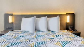 Ein Hotelzimmer mit einem Bett, zwei Nachttischen und einem Kopfteil mit integrierter Beleuchtung.