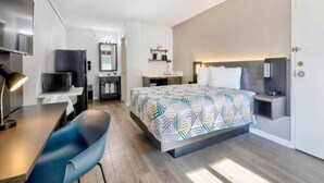 A modern hotel room with a bed, desk, chair, and a small kitchenette. - 1 King Bed | Non-Smoking, Kitchen (Effingham)