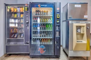 Trois distributeurs automatiques proposent divers produits, notamment des collations et des boissons.